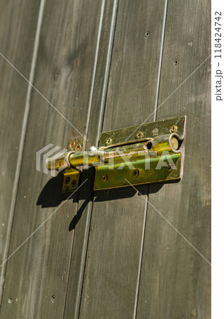 wooden door with a metal bolt lock, showcasing texture and detail in security. High quality photo 118424742