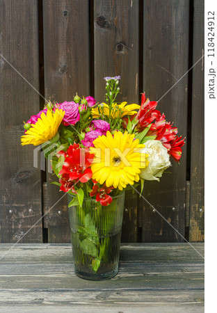bouquet of colourful flowers in glass vase on the wooden background . High quality photo bouquet of colourful flowers in glass vase on the wooden background . High quality photo 118424912