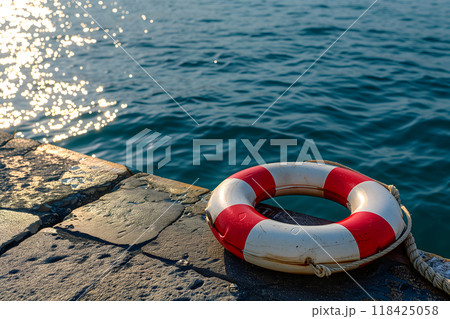lifebuoy on concrete pier with clear blue sea in the background 118425058