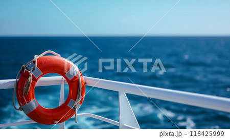 lifebuoy attached to a ship's white railing, with the clear blue sea in the background 118425999