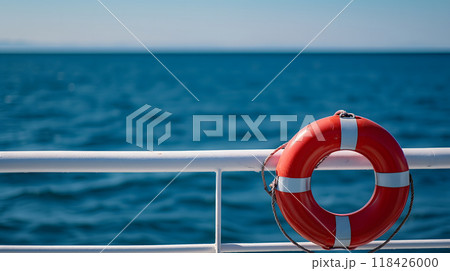 lifebuoy attached to a ship's white railing, with the clear blue sea in the background 118426000