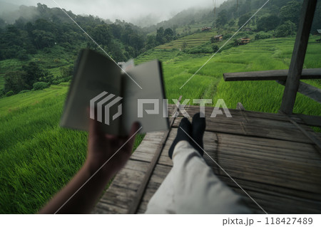 Sitting reading a book on the balcony of a house by the rice fields Sitting reading a book on the balcony of a house by the rice fields 118427489