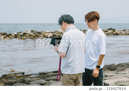 海岸でドローンを飛ばす男性 118427614