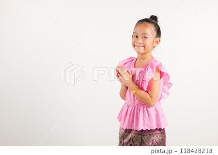 Portrait of Thailand kid girl smiling traditional Thai dress costume posing to pay respect in studio shot isolated white background, Happy kindergarten child sawasdee symbol or welcome Portrait of Thailand kid girl smiling traditional Thai dress costume posing to pay respect in studio shot isolated white background, Happy kindergarten child sawasdee symbol or welcome 118428218