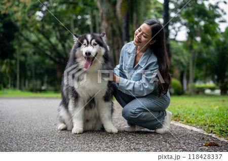 A woman is sitting and talking with her Siberian husky while taking it for a walk in the park. A woman is sitting and talking with her Siberian husky while taking it for a walk in the park. 118428337
