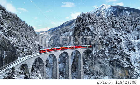 Snow falling and Train passing through famous mountain in Filisur, Switzerland. Train express in Swiss Alps snow winter scenery. 118428589