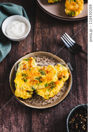 Crispy potato fritters with broccoli on a plate on the table vertical view 118430169