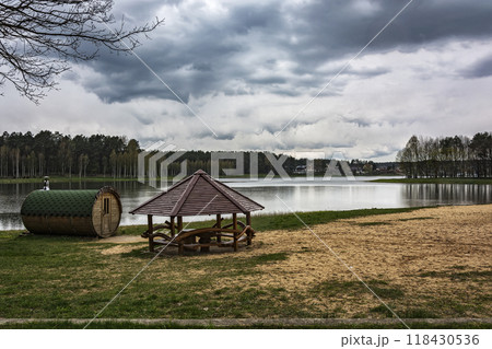 On the shore of the forest lake there is a bathhouse and a gazebo 118430536