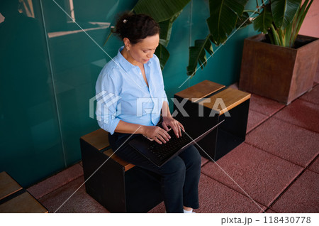 Businesswoman working on a laptop in a modern office space with natural light and indoor plants Businesswoman working on a laptop in a modern office space with natural light and indoor plants 118430778
