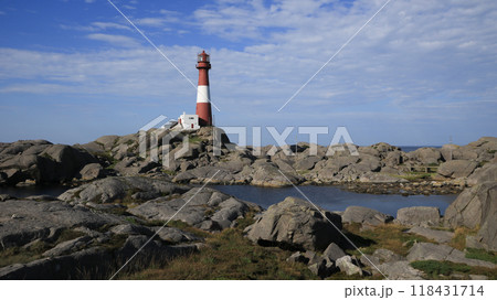 Red and white cast iron Eigeroy Lighthouse and anorthosite rock formations, Norway. 118431714