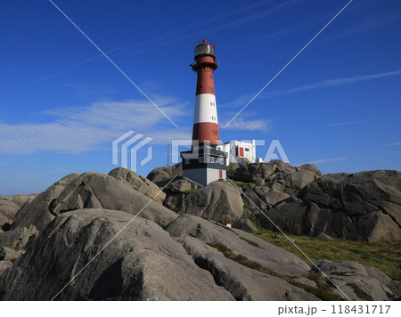 Red white Eigeroy Lighthouse and anorthosite rock formations, Norway. 118431717