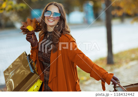 smiling elegant woman in brown trench coat with shopping bags smiling elegant woman in brown trench coat with shopping bags 118432442