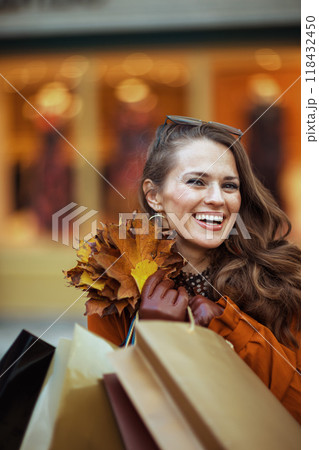 smiling modern woman in brown trench coat 118432450