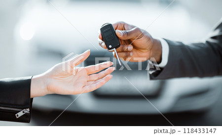 A person is receiving car keys from another person outdoors. The person giving the keys is wearing a suit jacket, and the person receiving the keys is wearing a leather jacket, cropped A person is receiving car keys from another person outdoors. The person giving the keys is wearing a suit jacket, and the person receiving the keys is wearing a leather jacket, cropped 118433147
