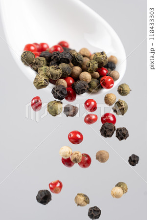 Different types of peppercorns pouring. Red, green, white and black pepper. 118433303