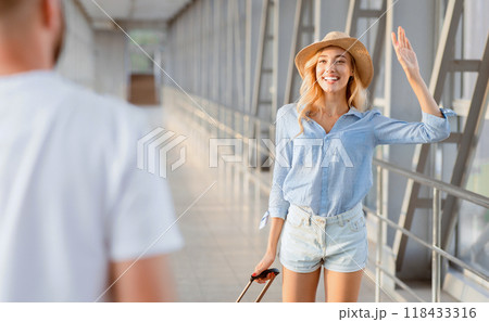 Meeting At Airport. Young girl waving to her glad boyfriend after long separation, selective focus Meeting At Airport. Young girl waving to her glad boyfriend after long separation, selective focus 118433316