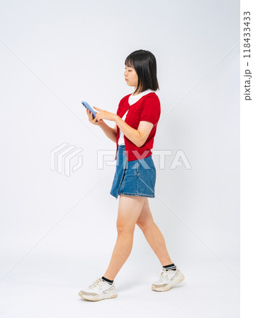 スマホを見ながら歩く女の子の全身写真 118433433