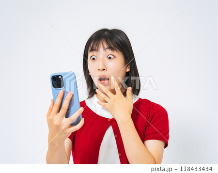 スマホを見て驚く女の子 118433434