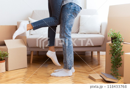 Relocation Concept. Loving Afro Husband Lifting His Wife Among Moving Boxes Standing In New Apartment. Cropped Relocation Concept. Loving Afro Husband Lifting His Wife Among Moving Boxes Standing In New Apartment. Cropped 118433768