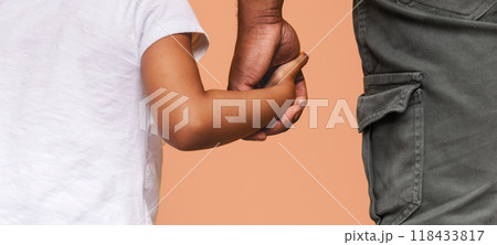 Cropped of father and his daughter holding hands. The father is wearing dark grey pants with a large pocket on the side. The daughter is wearing a white shirt and is holding her fathers hand 118433817