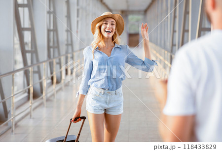 Man meeting sister at airport terminal, woman coming to new city and waving hand 118433829
