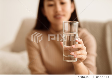 Healthcare Concept. Asian Girl Holding Glass of Mineral Water, Stretching to Camera Healthcare Concept. Asian Girl Holding Glass of Mineral Water, Stretching to Camera 118433873