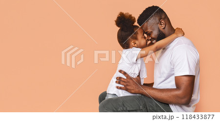 A happy black father and his daughter share a tender moment together. The little girl is embracing her father, her arms wrapped around his neck, while he gently holds her with one hand. 118433877
