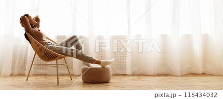 Weekends Finally. Relaxed Girl Sitting on Modern Chair near Window, Enjoying Morning 118434032