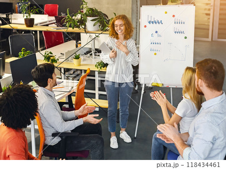 Woman team leader making presentation for colleagues in office, coworkers clapping hands, free space 118434461