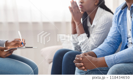 Marital psychotherapy. Unrecognizable african american couple sitting on couch at counselor's office, crop 118434650