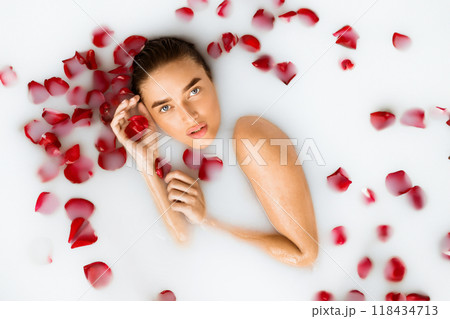 Sexy woman lying in milk bath with red rose petals, top view, crop Sexy woman lying in milk bath with red rose petals, top view, crop 118434713