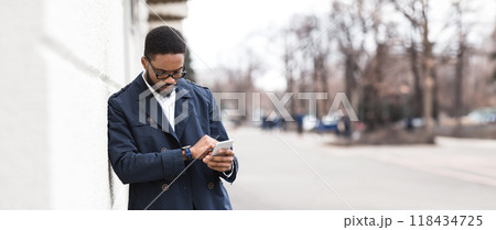 African American businessman walking to office by street, holding phone, checking time, looking at watch, panorama with copy space 118434725