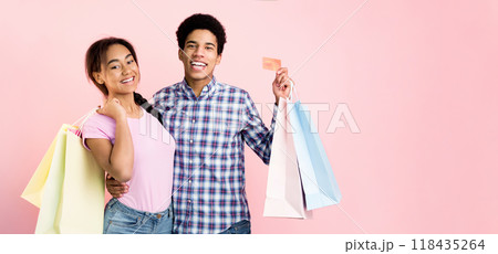 Happy teenagers with shopping bags over pink background, posing after making purchases Happy teenagers with shopping bags over pink background, posing after making purchases 118435264