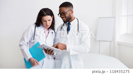 Afro doctor giving advice to his colleague during meeting with staff in hospital Afro doctor giving advice to his colleague during meeting with staff in hospital 118435275