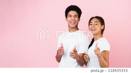 Gotcha. Teen couple pointing fingers at camera, posing on pink studio background 118435353