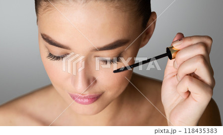 Doing Makeup. Woman Applying Mascara on Eyelashes with Brush, Grey Background 118435383