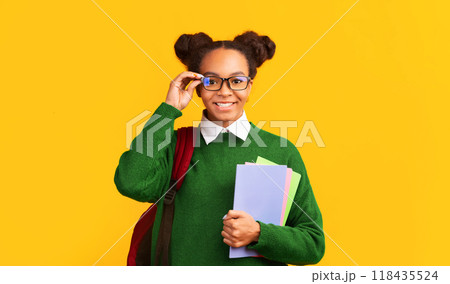 Eyesight. Happy afro teen girl touching glasses, holding colorful notebooks or folders, panorama, free space for promo 118435524