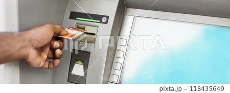 Close up of black man using ATM with gold credit card, panorama, copy space Close up of black man using ATM with gold credit card, panorama, copy space 118435649
