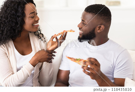 A couple shares a slice of pizza while smiling at each other. 118435810