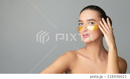 Beauty Woman with Eye Patches Showing Effect of Perfect Skin on Grey Studio Background Beauty Woman with Eye Patches Showing Effect of Perfect Skin on Grey Studio Background 118436021