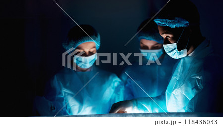 Surgeons performing surgical operation in dark operating room, focus on african-american doctor 118436033