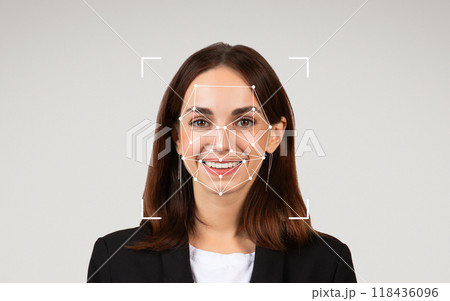 A woman in professional attire smiles as facial recognition patterns are superimposed on her face. A woman in professional attire smiles as facial recognition patterns are superimposed on her face. 118436096