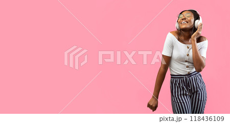 Happy Afro Woman In Wireless Headphones Listening To Music And Dancing On Yellow Background In Studio. Panorama, Empty Space 118436109