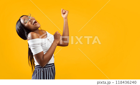 Happy Young Woman Shaking Fists Gesturing Yes Celebrating Success Standing Over Orange Background In Studio. Panorama, Copy Space Happy Young Woman Shaking Fists Gesturing Yes Celebrating Success Standing Over Orange Background In Studio. Panorama, Copy Space 118436240