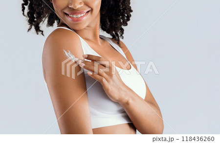 Young black woman using cream after shower for body care, skin care products concept, cropped 118436260