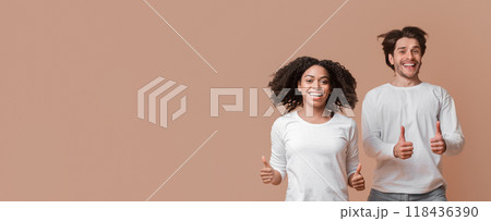 Like. Joyful Interracial Couple Jumping In The Air And Showing Thumbs Up Over Yellow Background With Empty Space 118436390