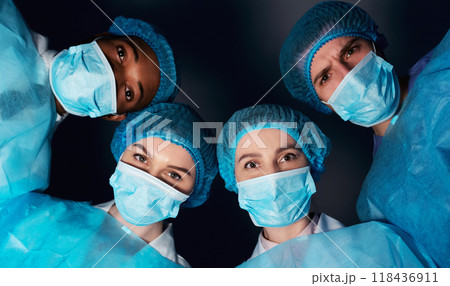 Patient pov. Team of surgeons looking at patient after performing operation in dark room Patient pov. Team of surgeons looking at patient after performing operation in dark room 118436911