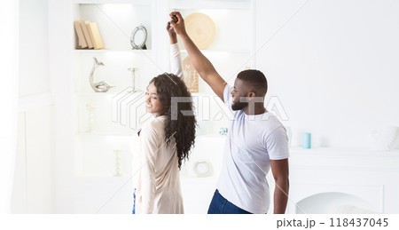 A couple dances in a white room, the man leading the woman with a smile. A couple dances in a white room, the man leading the woman with a smile. 118437045