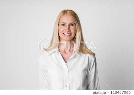 A smiling woman with blonde hair and wearing a white button-down shirt stands against a white background. Her bright white shirt has a collar and long sleeves A smiling woman with blonde hair and wearing a white button-down shirt stands against a white background. Her bright white shirt has a collar and long sleeves 118437090