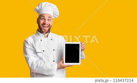 Cooking Food App. Joyful Male Chef Holding Digital Tablet Showing Blank Screen Standing Over Yellow Studio Background. Mockup 118437214